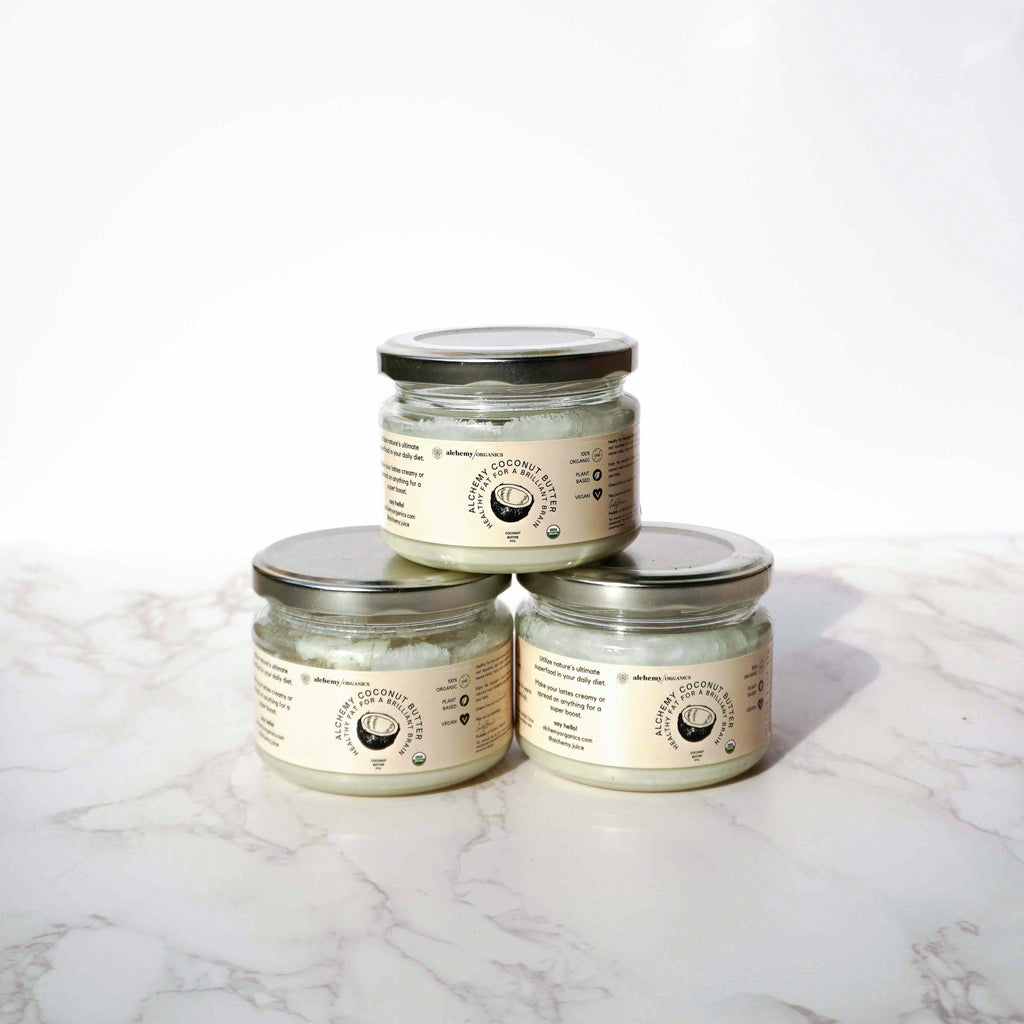 3 glass jars filled with coconut oil / butter with a beige label and silver lid with a marble and white backdrop