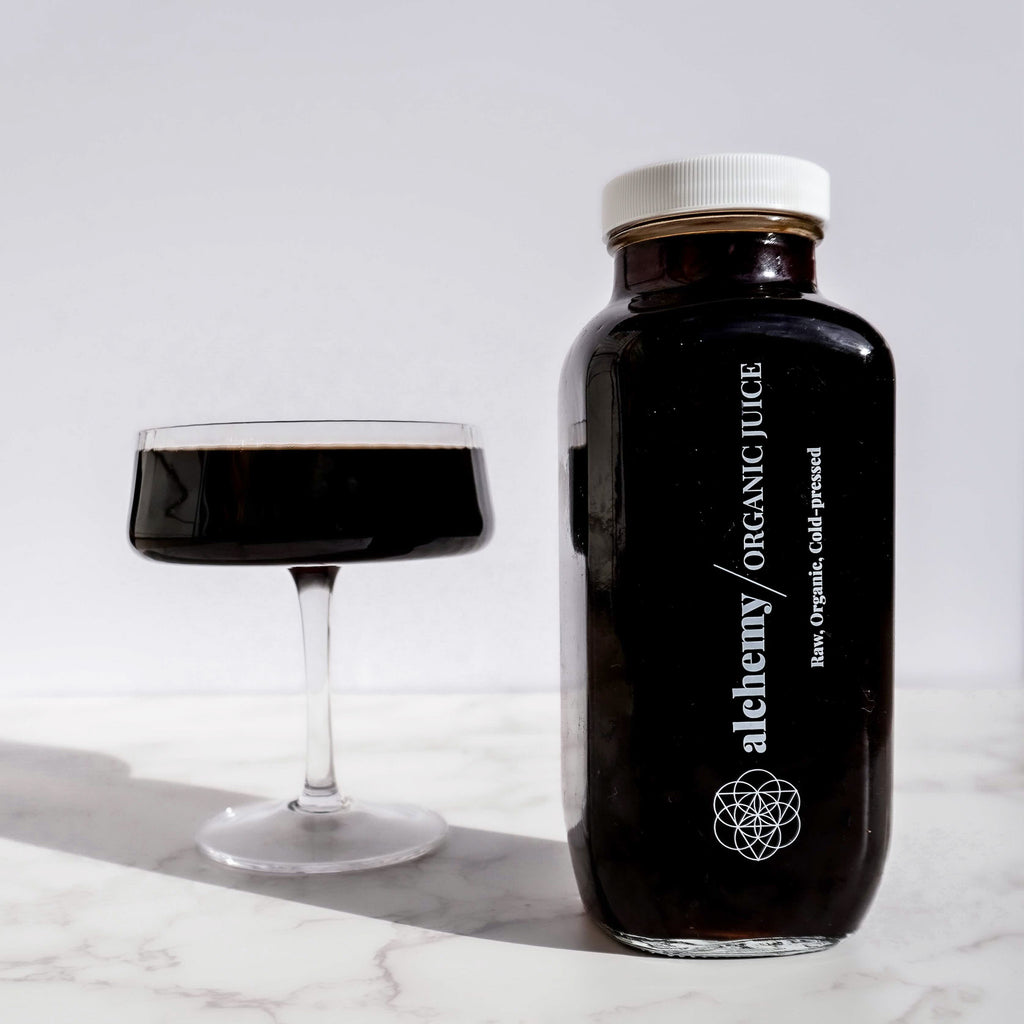 Glass bottle filled with organic and alkaline cold brew coffee and a cocktail glass filled with dark liquid